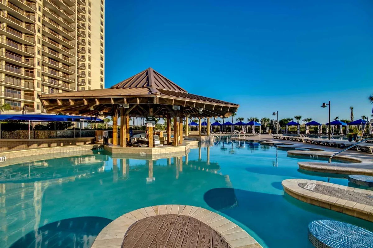 An inviting exterior pool area with loungers and a gazebo, set amid lush landscaping. The image captures both the social and peaceful aspects of the resort, suggesting opportunities for sunbathing, swimming, and social gatherings by the water.