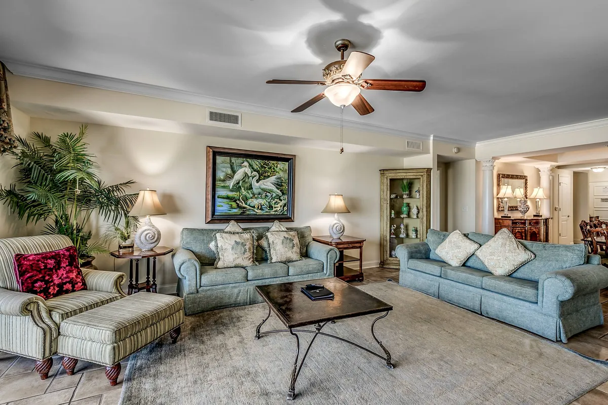 A cozy living area with sofas, a coffee table, elegant artwork, a floor lamp, and a potted plant. The composition feels intimate yet spacious, promoting both relaxation and casual socializing in a tastefully decorated setting.